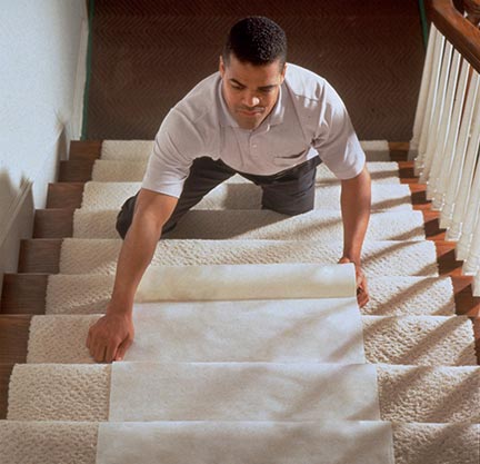 Man on stairs placing carpet.