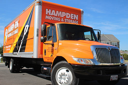 Orange Hampden truck parked with a blue sky background.